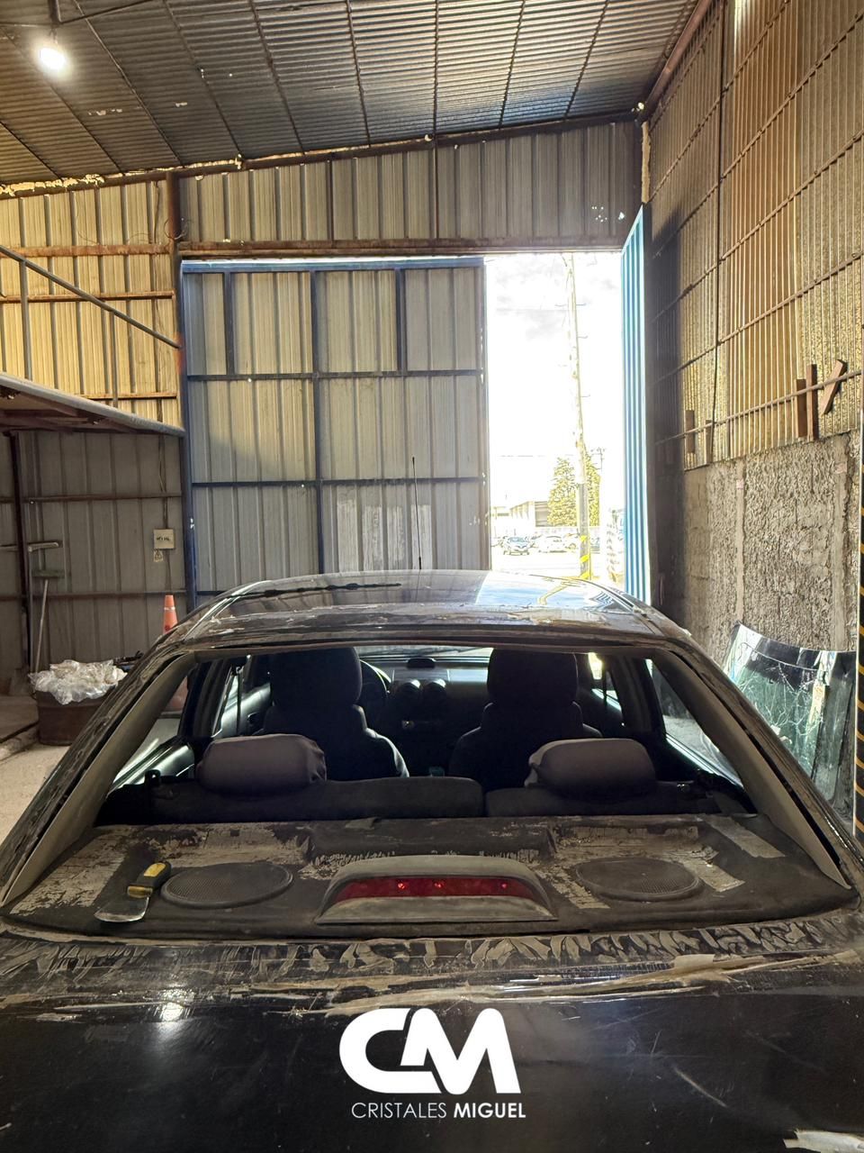 Vista trasera de un automóvil dentro de un taller con la ventana trasera quitada