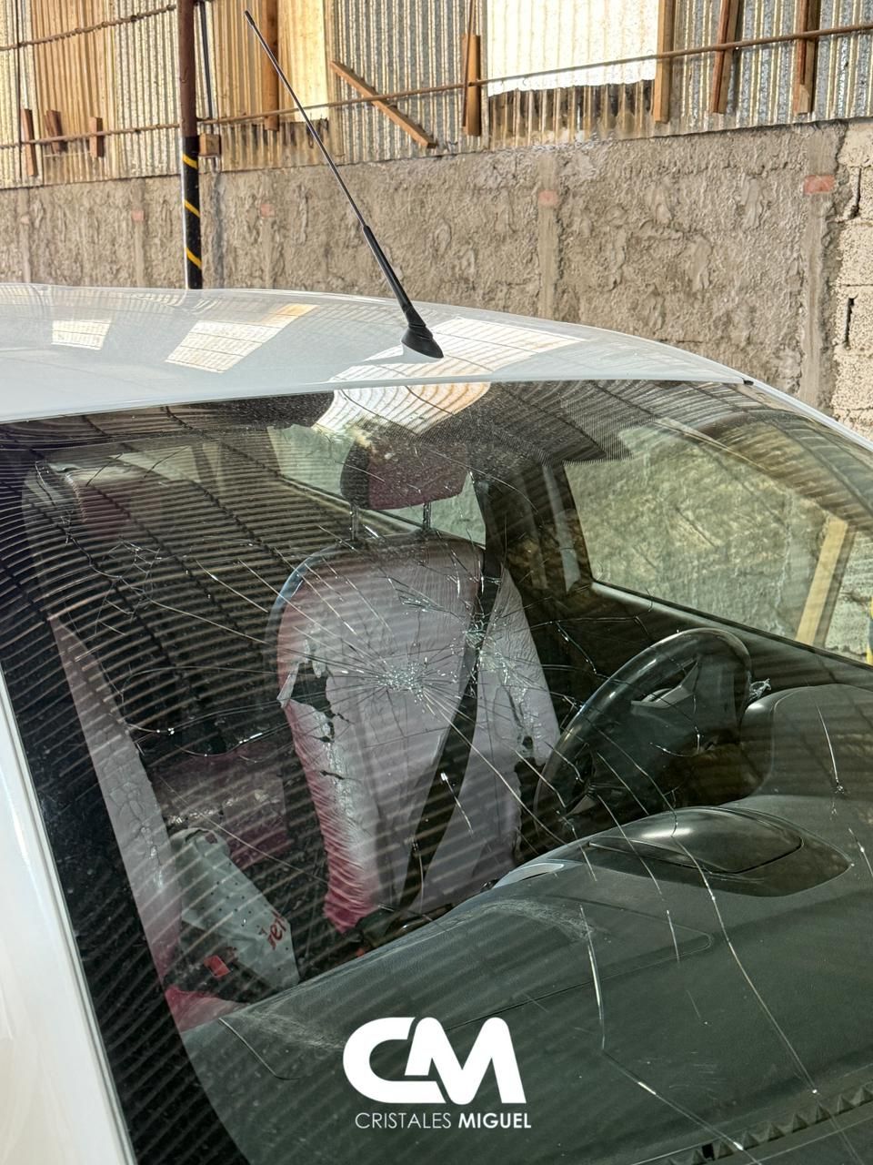 Coche blanco con airbags desplegados y parabrisas destrozado.