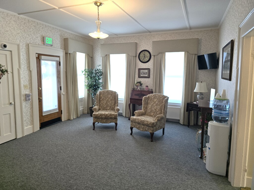 Bright waiting room with two armchairs, water cooler, windows, and carpeted floor