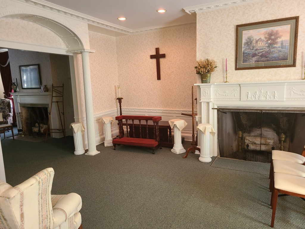 Elegant living room with fireplace, cross on wall, red bench, and arched doorway