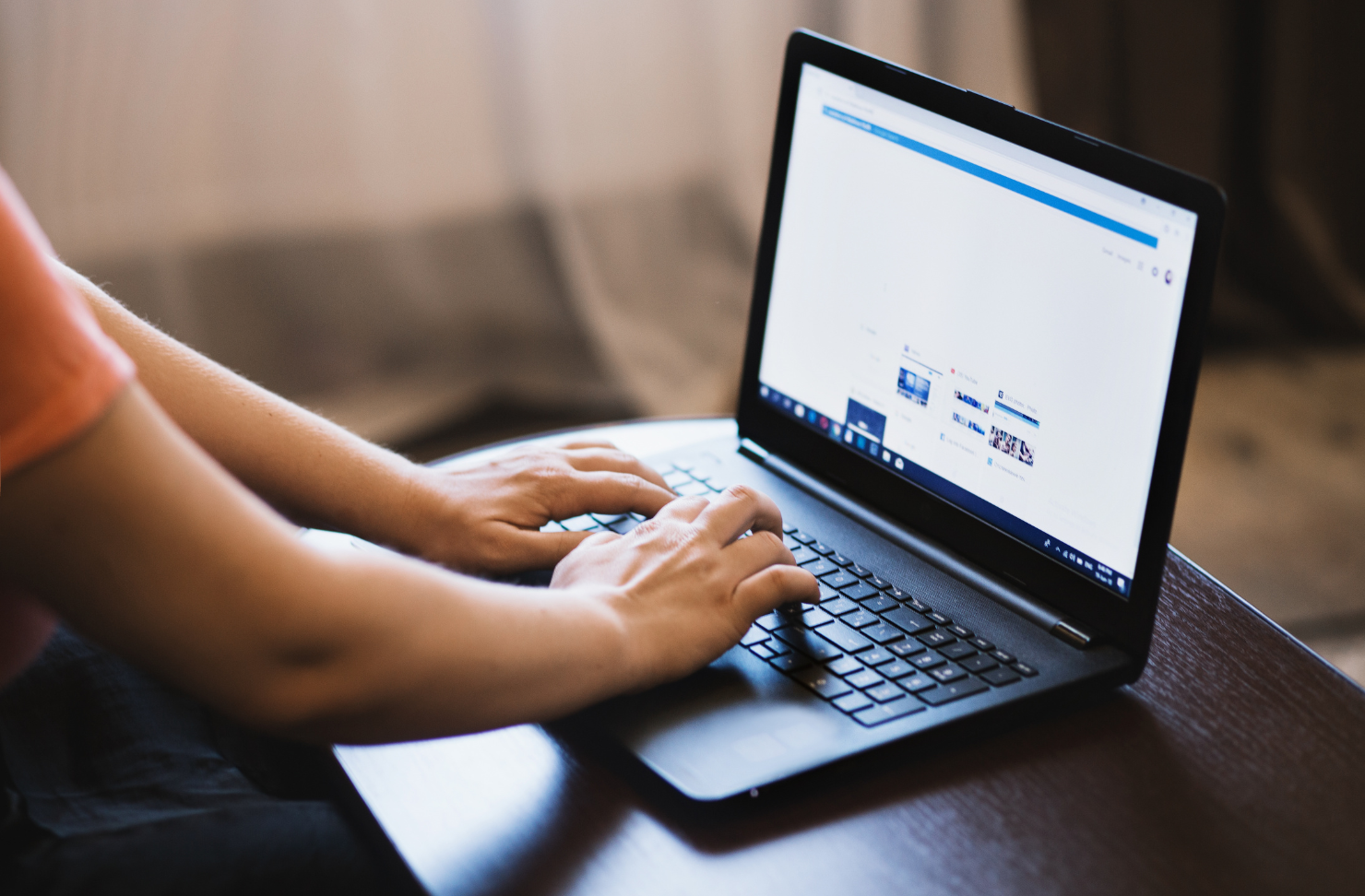 A person is typing on a laptop computer on a table.