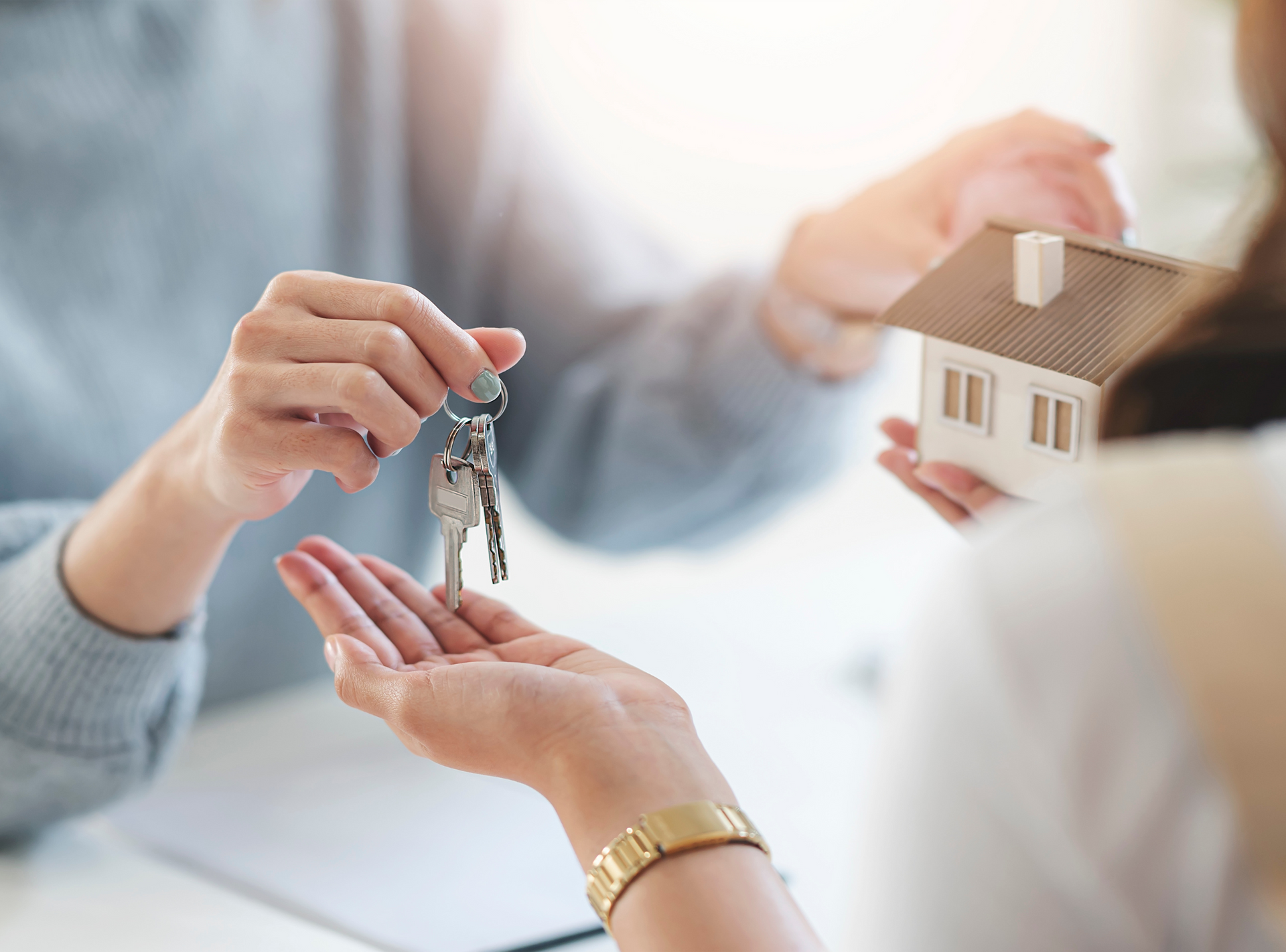 A woman is holding a model house and keys in her hands.
