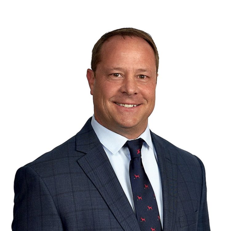 Headshot of a smiling man in a navy suit and tie against a white background