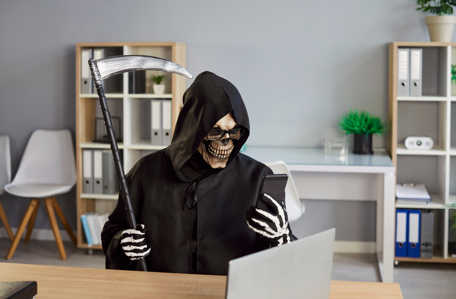Grim reaper at a desk representing wire fraud threats in real estate