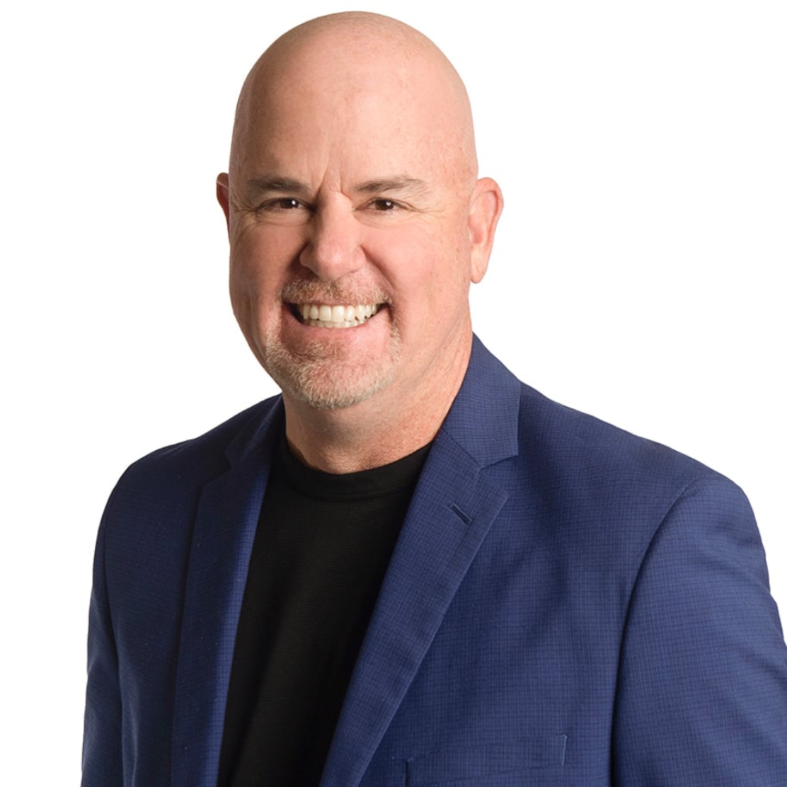 Smiling bald man in a blue blazer and black shirt on a white background