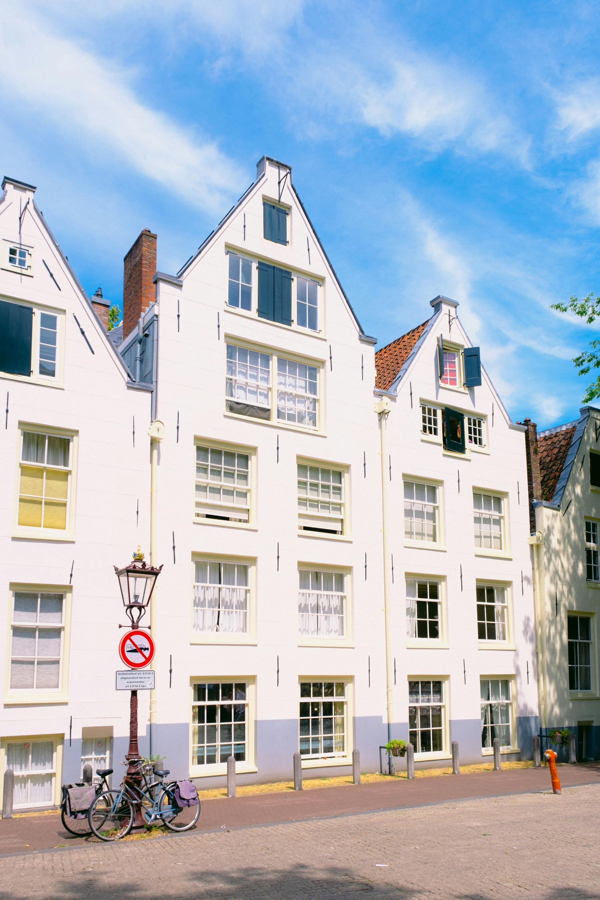 White stepped-gable buildings on a sunny street with bicycles and a lamppost under a blue sky