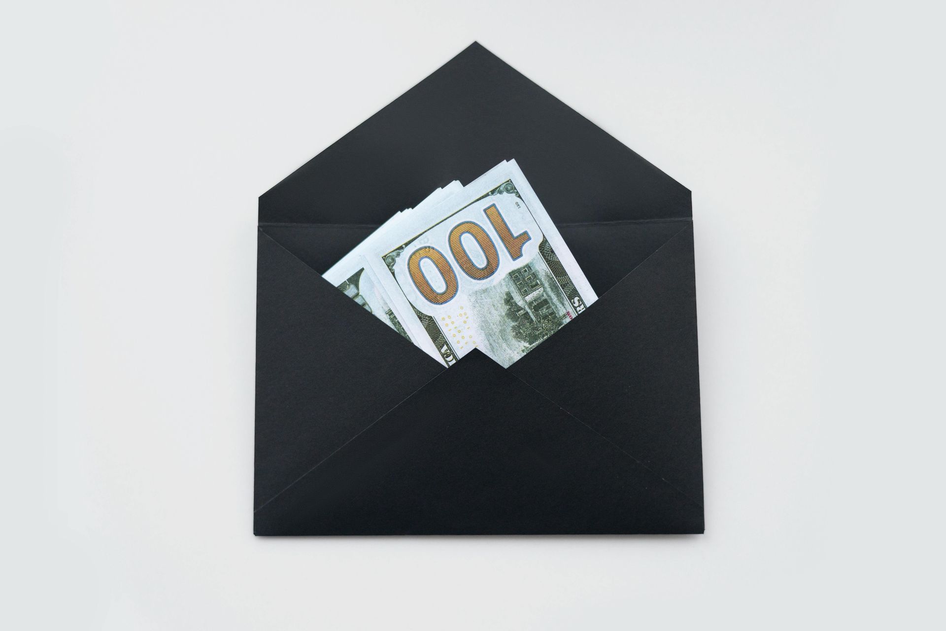 Black envelope with a stack of 100 dollar banknotes peeking out