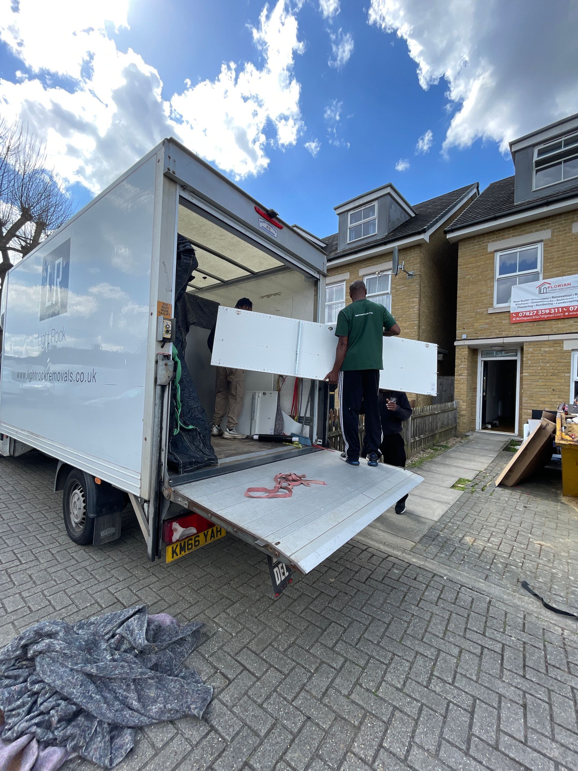 People loading furniture into a white moving truck on a residential street.