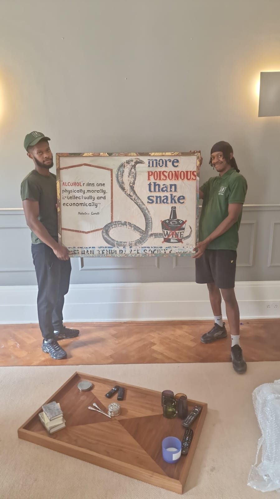 Two Light Rock Removals movers carefully carrying a framed artwork