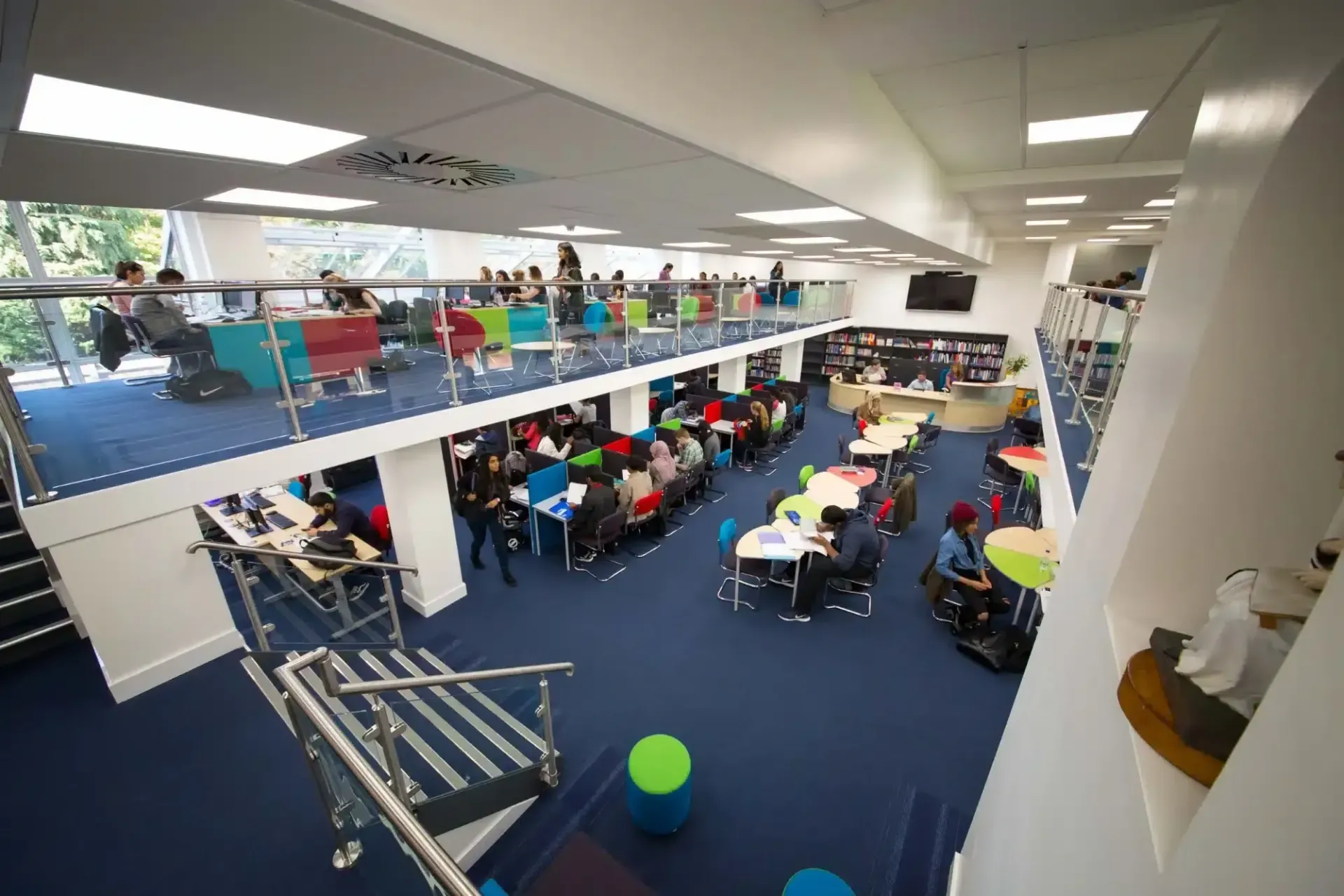 Students studying in a modern two-storey library in Harrow