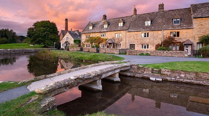 Stone cottages beside a stream at sunset