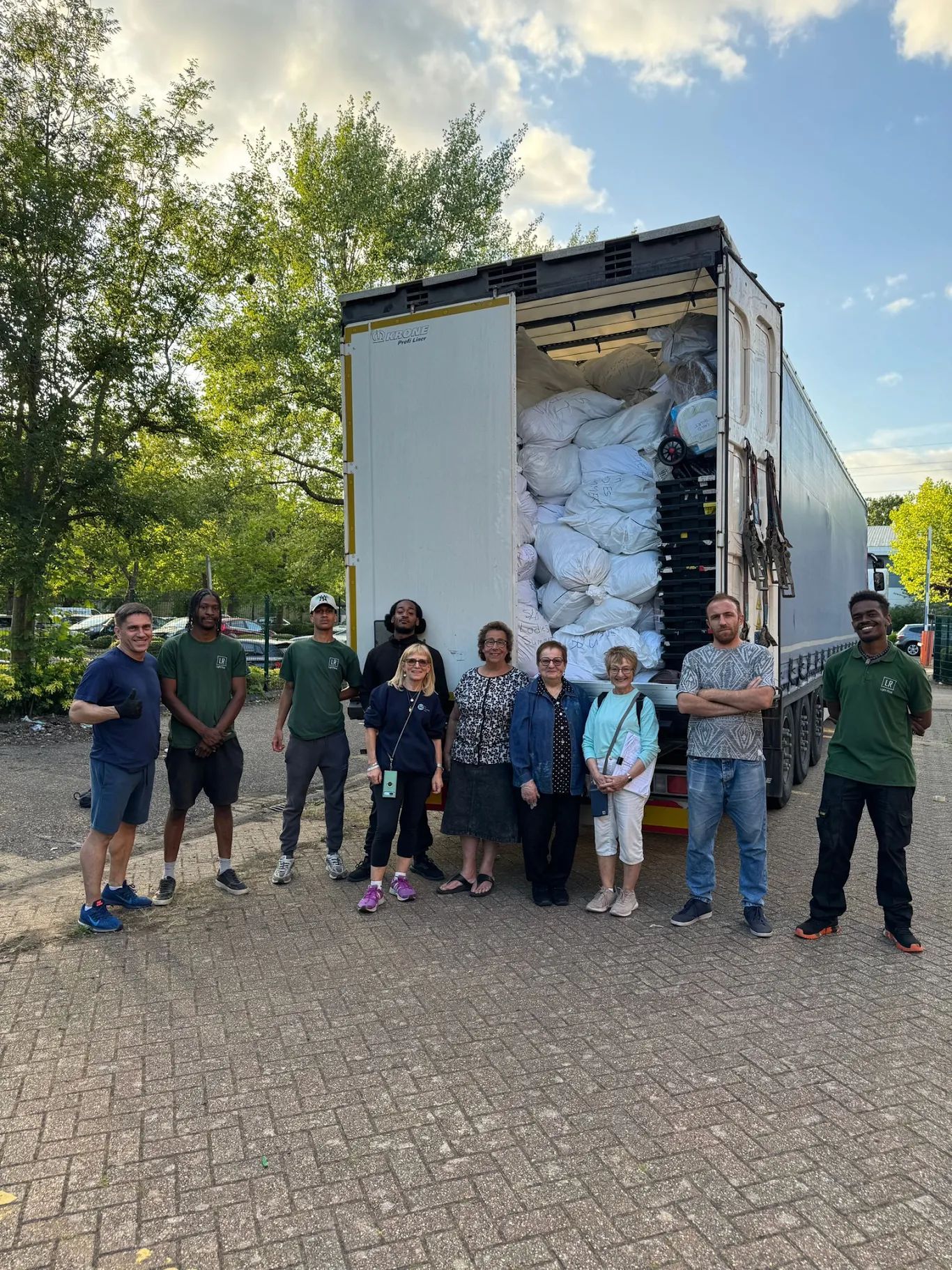 Group of people standing in front of a semi-truck with an open cargo door filled with white bundles.
