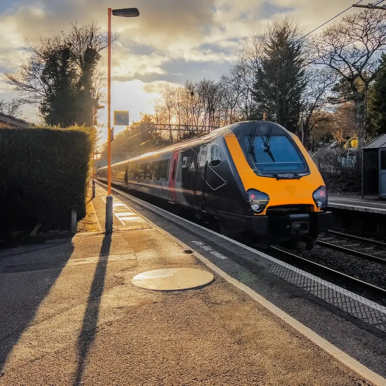 Train arriving at a station platform at sunset