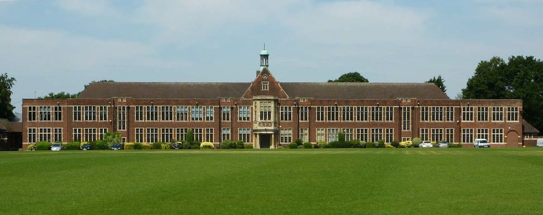 Brick school building with green lawn and blue sky.
