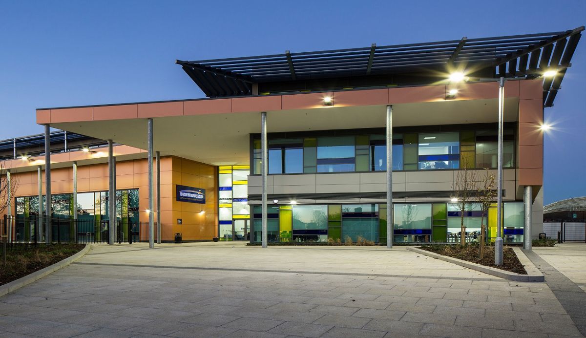 Contemporary school building lit up at dusk in Northwood