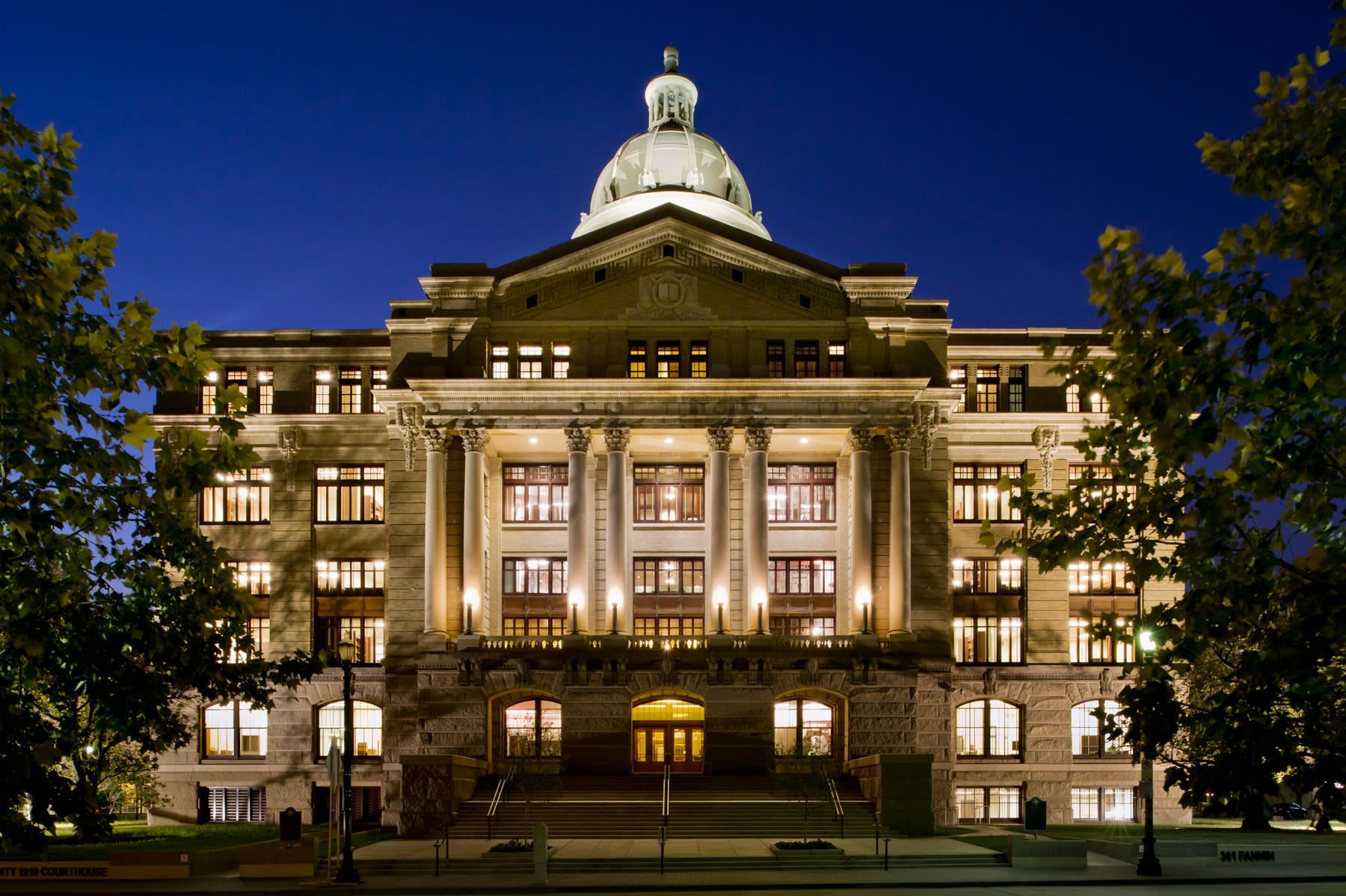 A large building in Sugar Land with a dome on top is lit up at night