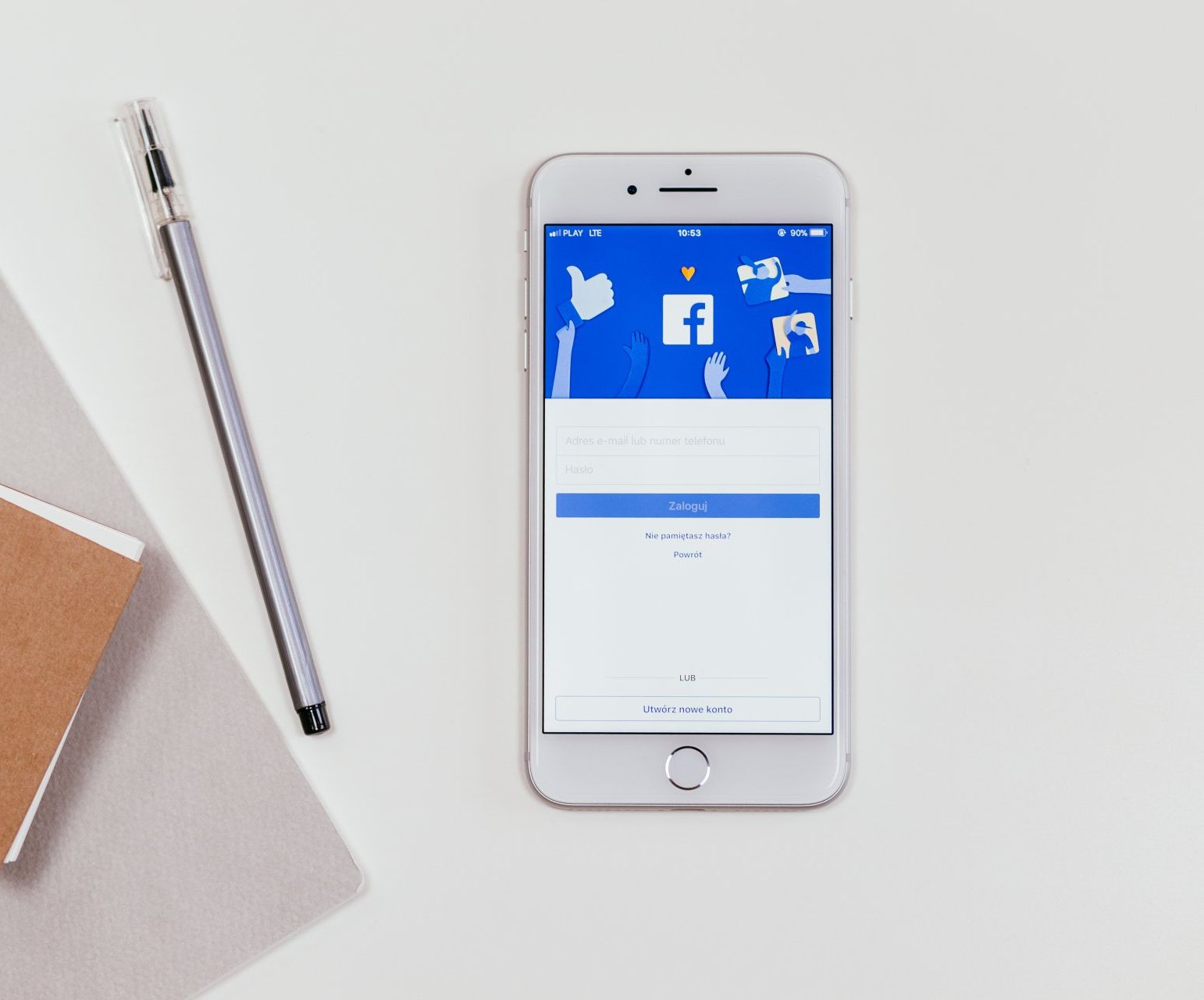 Cell phone on a desk displaying the Facebook home screen