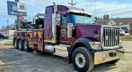 A large purple tow truck is parked in a gravel lot. A large purple tow truck is parked in a gravel lot.