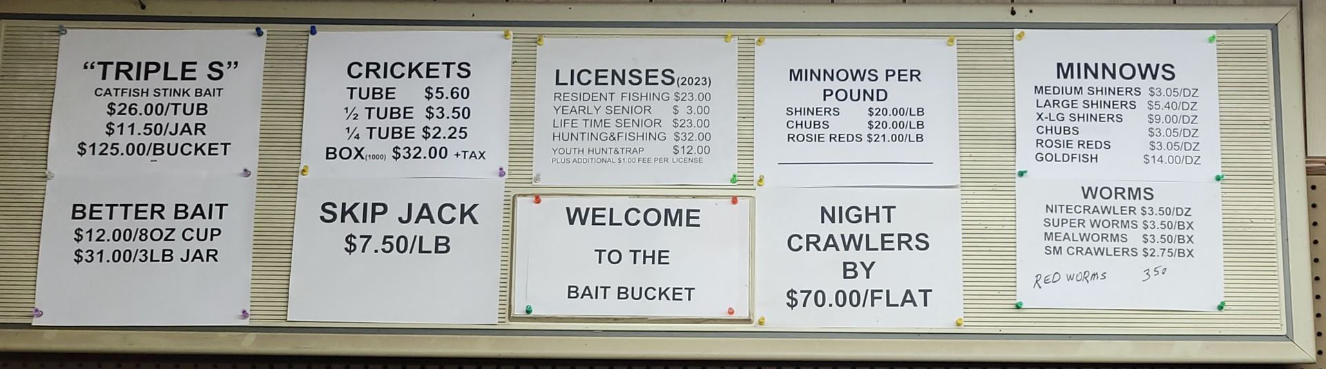 A bulletin board with handwritten signs listing prices and menus for food and services.