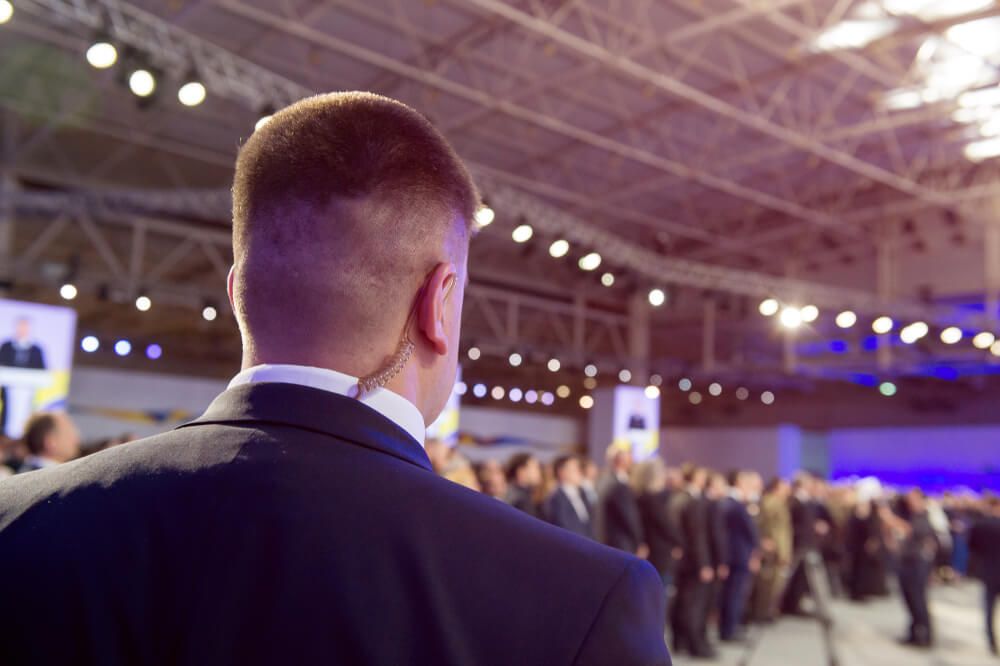 A Man in a Suit is Standing in Front of a Crowd of People — AVI Protection Group Pty Ltd in West Kempsey, NSW