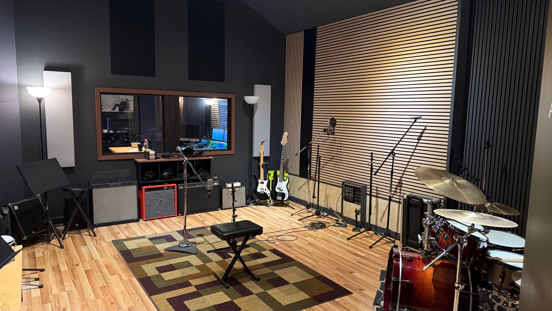 Recording studio with drum kit, guitars, speakers, and soundproof wall panels