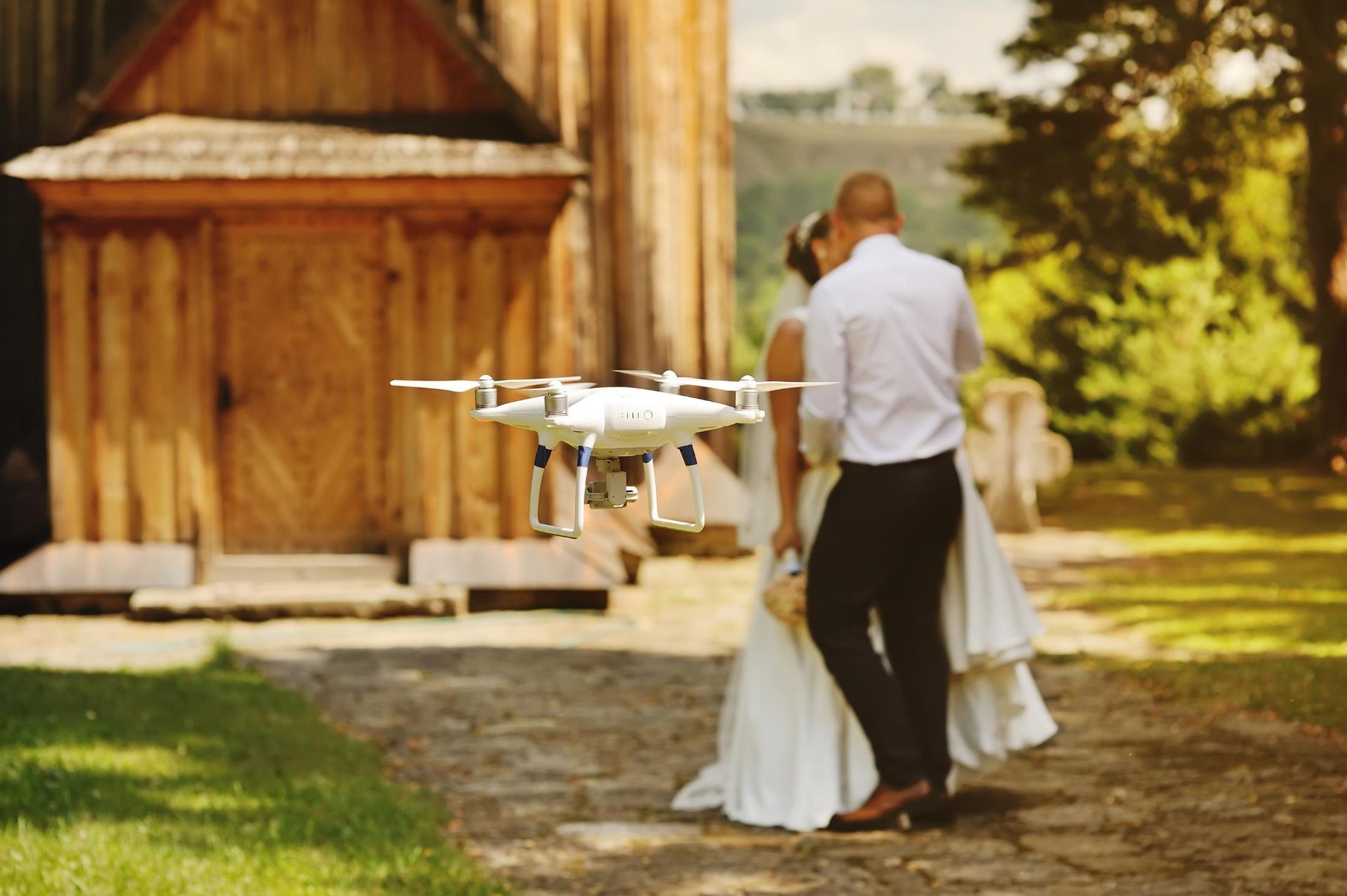 A bride and groom are standing next to a drone.