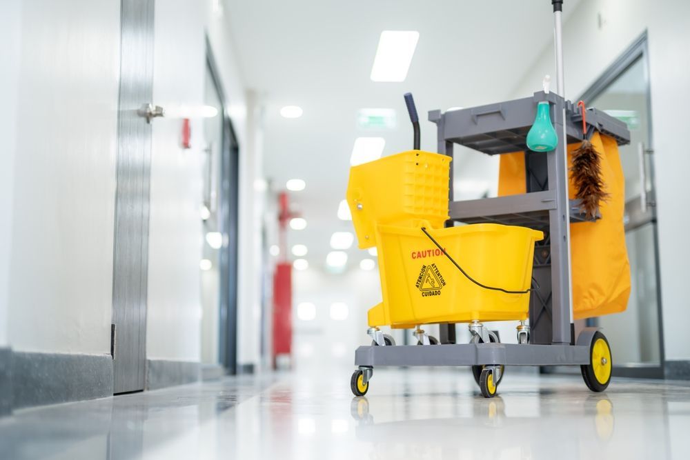 A cleaning cart with a yellow bucket and mop in a hallway.