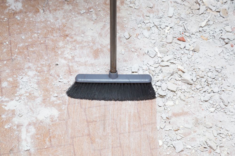 A broom is sitting on top of a wooden floor.