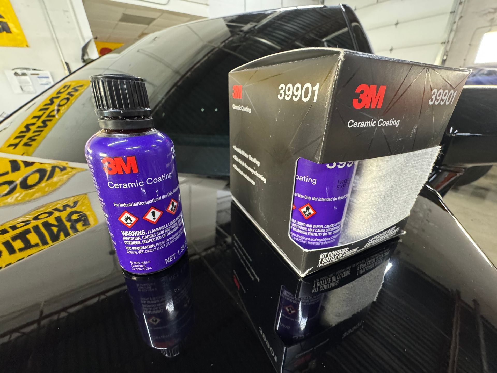 A purple 3M Ceramic Coating bottle and its matching black box sitting on the hood of a car.