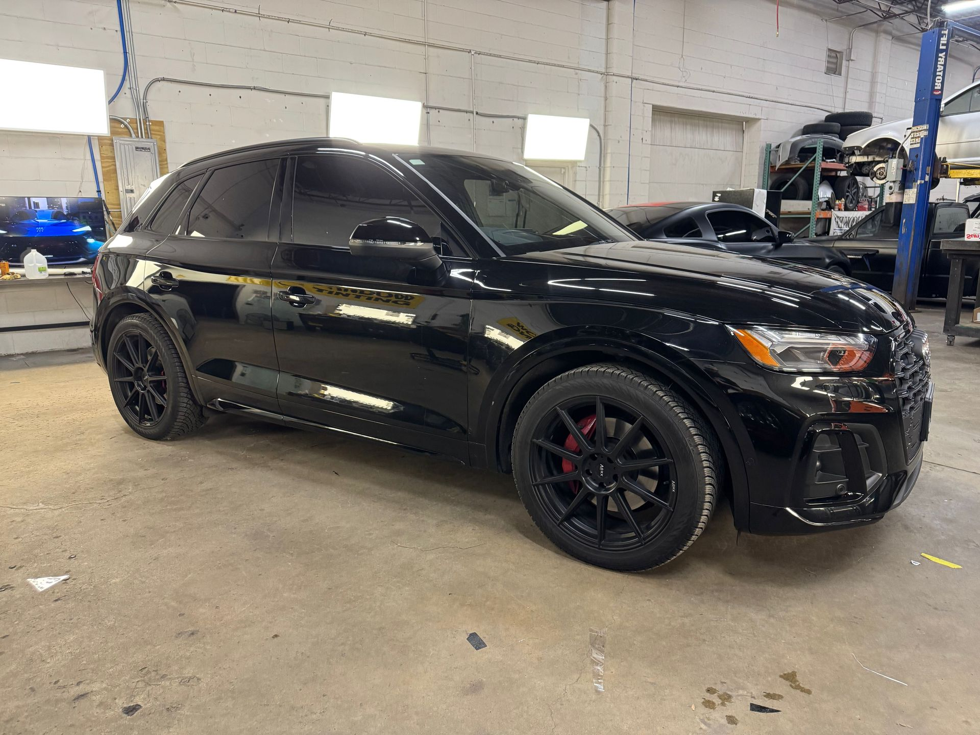 A black Audi SUV parked in an auto repair shop with black rims and red brake calipers.