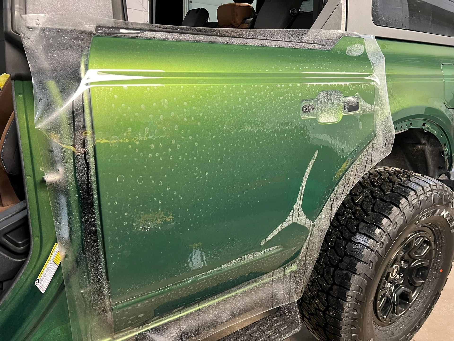 Two people applying a thin, clear protective film onto the hood of a car.