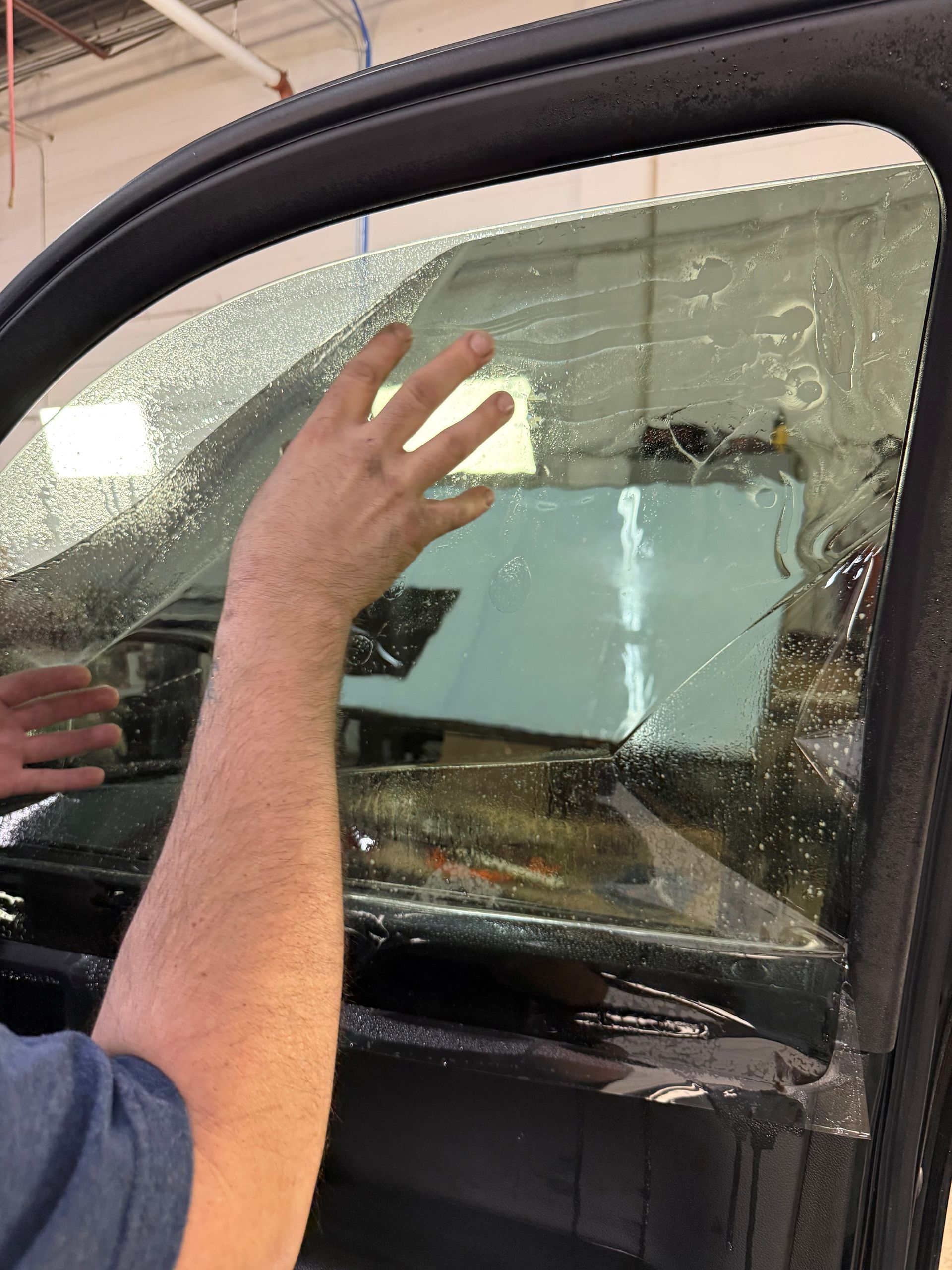 Shattered car window being inspected by a person in a blue shirt