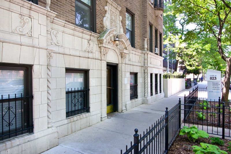 the exterior of a building with a sidewalk and a wrought iron fence