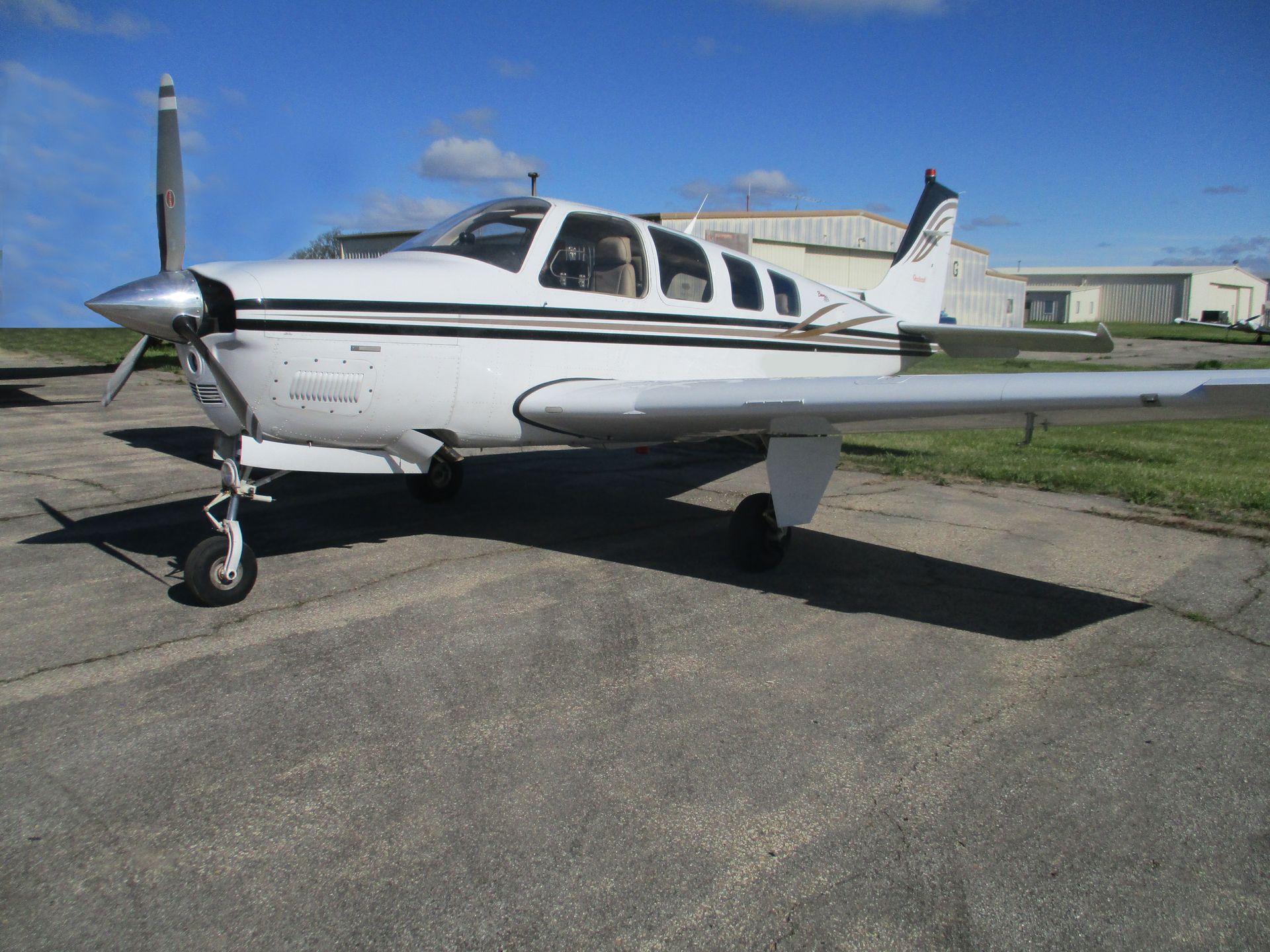 White and black airplane parked on an asphalt surface under a clear, blue sky.