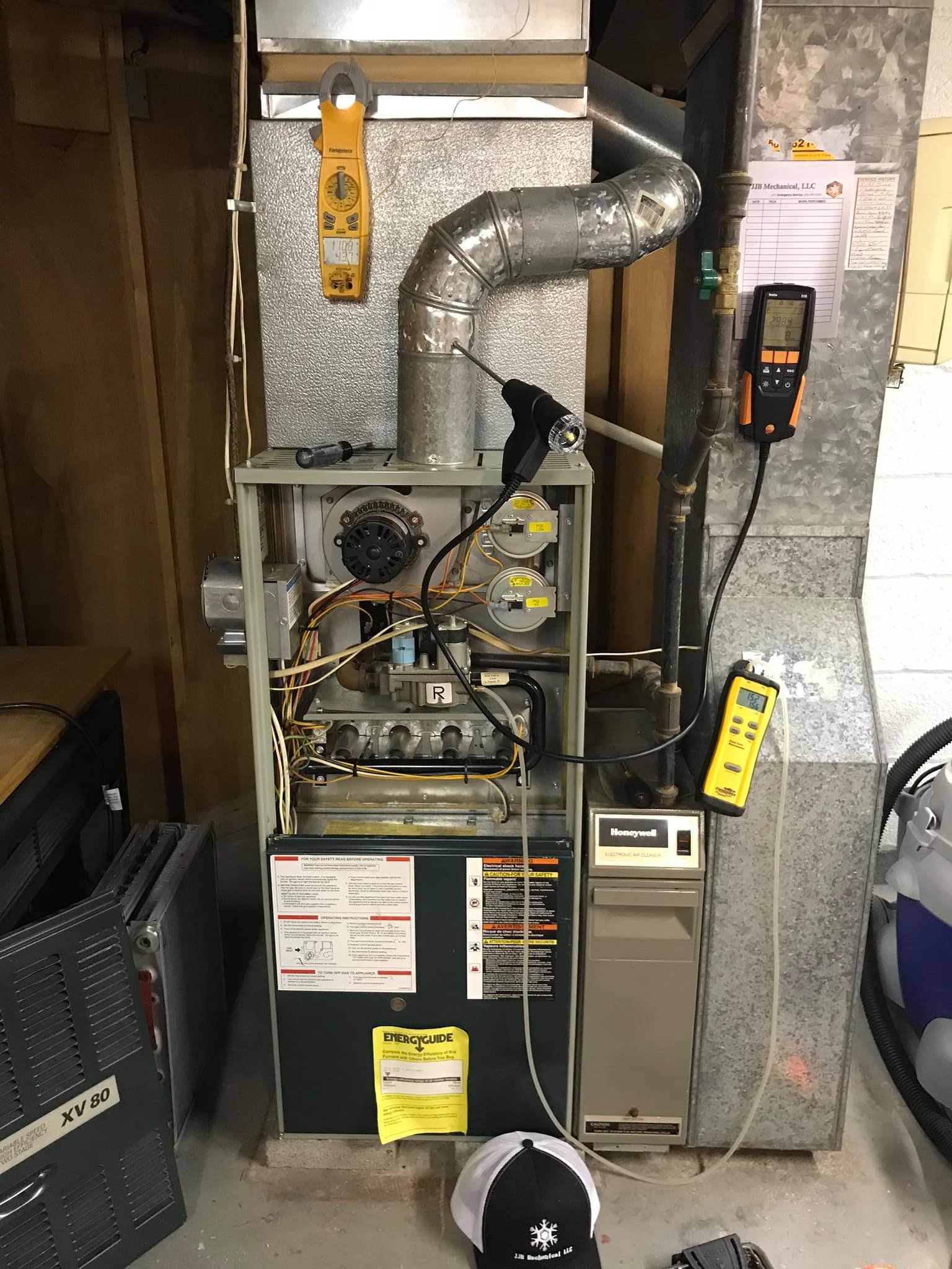 A man is working on a furnace in a basement.