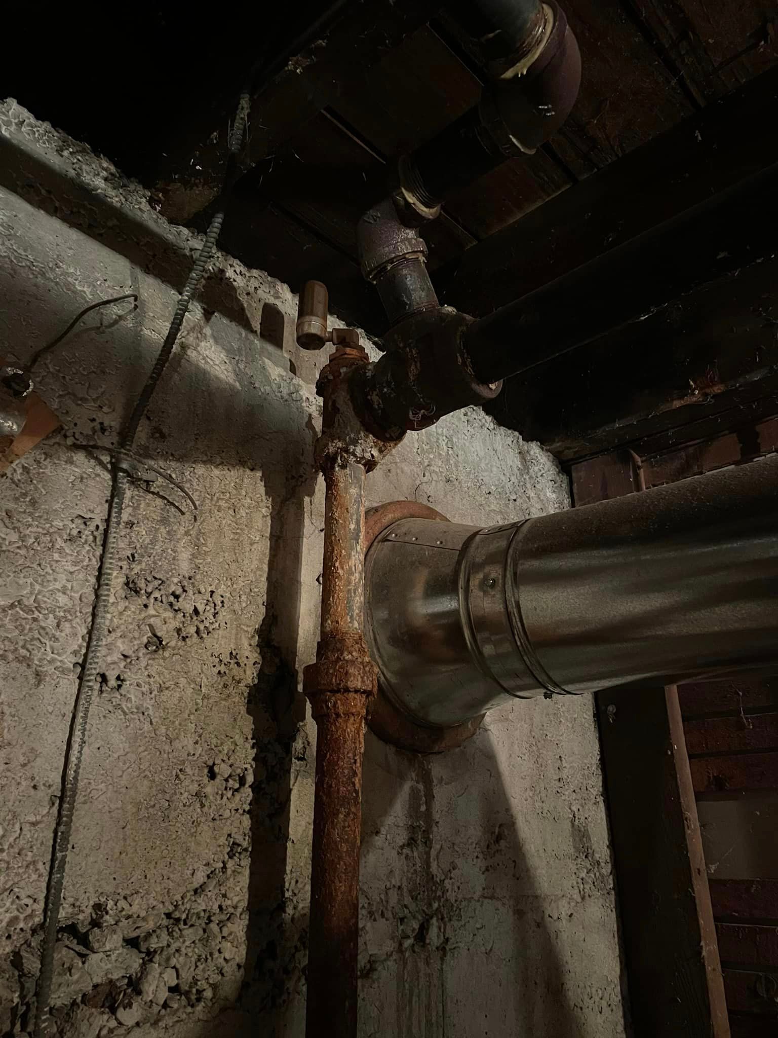 A close up of a rusty pipe in a basement.