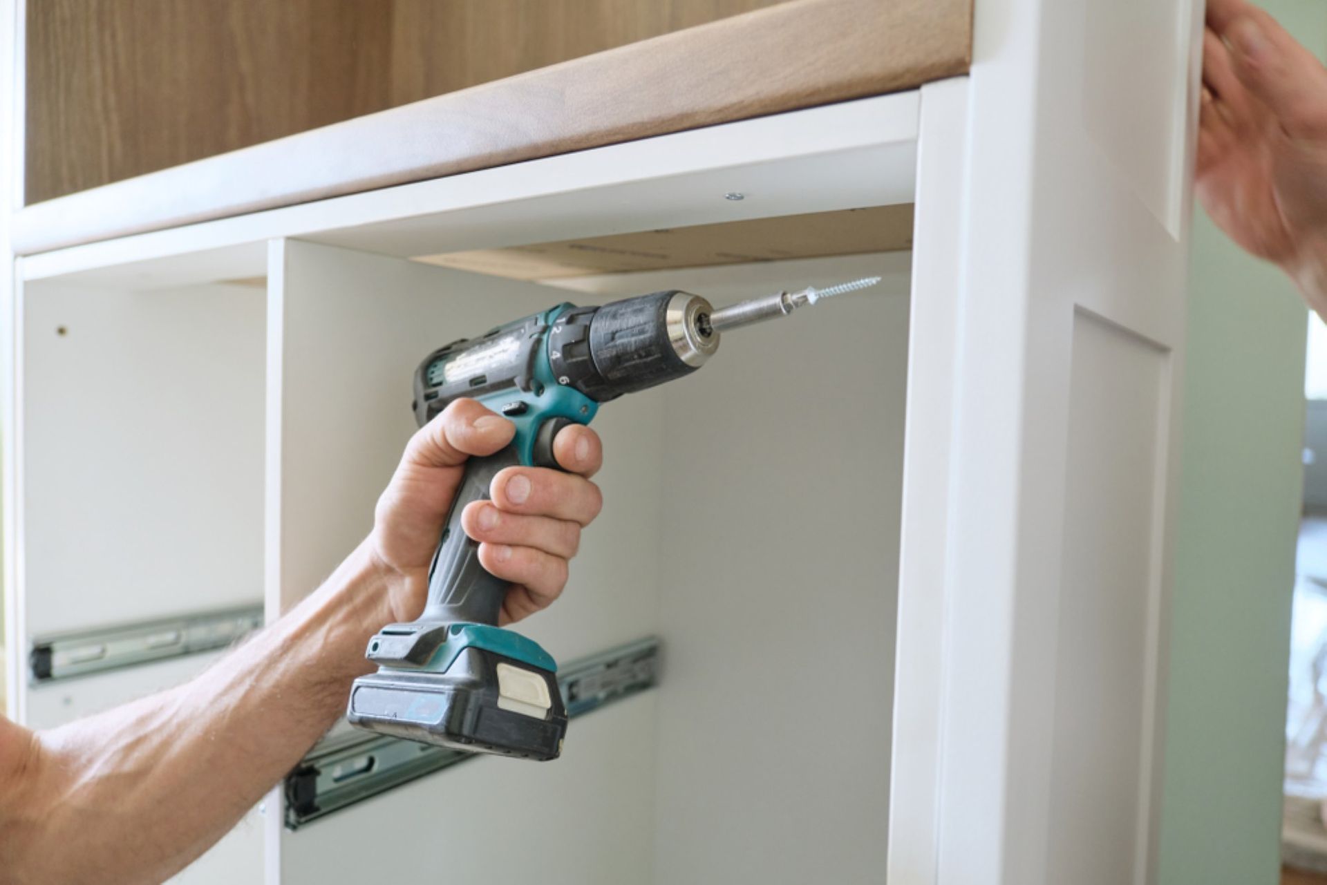 A Man is Using a Cordless Drill — Connolly Bros Kitchens In Casino, NSW