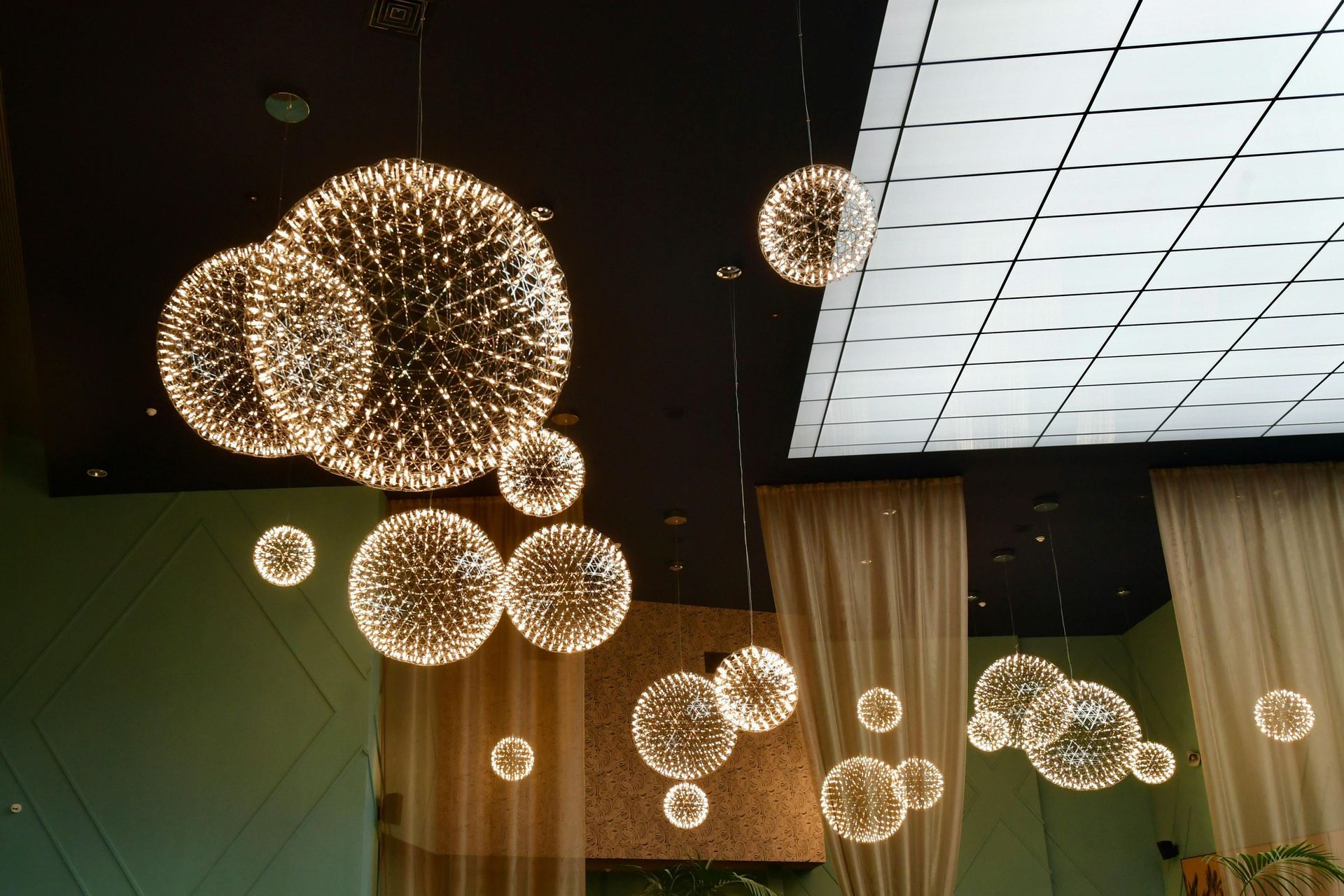 Modern interior with hanging spherical pendant lights and a large illuminated ceiling panel