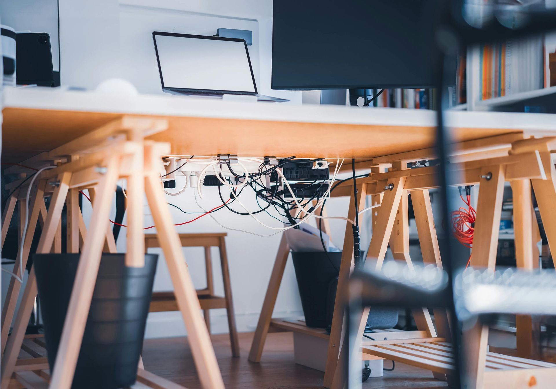 Modern office with wooden chairs, desk, laptop, and wall-mounted monitor in a bright workspace
