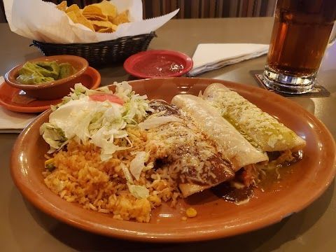 Plate of Mexican food: enchiladas, rice, salad, salsa, chips, guacamole, and a beer.