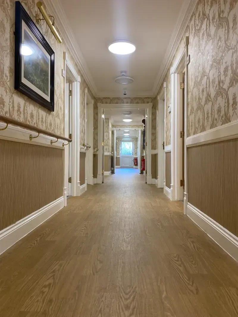 Woodlands Manor Care Home | A long hallway with wooden floors and a picture on the wall.