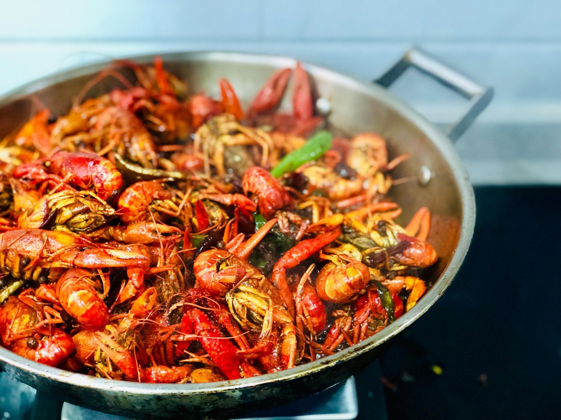 A close-up view of a large metal pan filled with freshly cooked, bright red crawfish in a spicy, seasoned sauce.