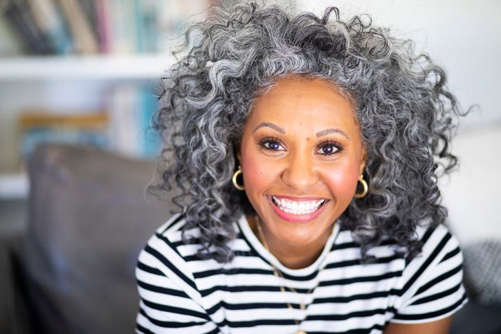 A woman is pointing at her teeth and smiling.