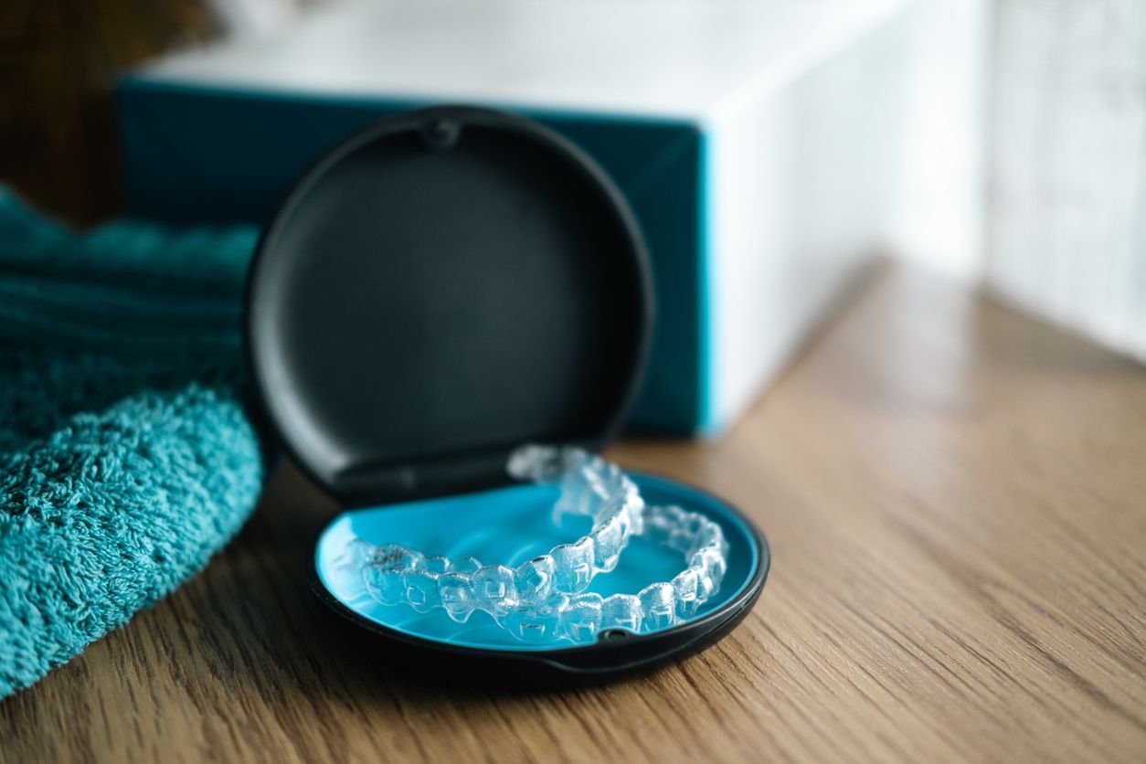 A pair of clear braces in a case on a wooden table.