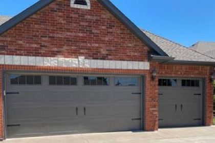 Brick house exterior with two gray garage doors under a blue sky