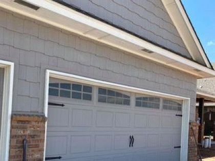White double garage door on a house exterior with brick siding and a sloped roof