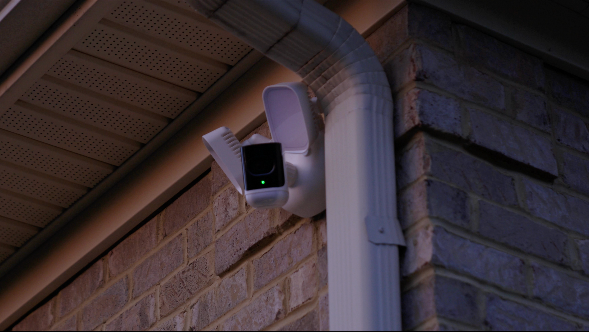 A security camera is mounted on the side of a brick building.