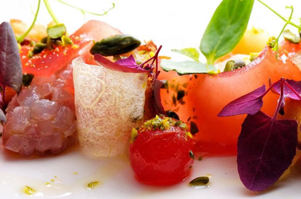 Eine Nahaufnahme eines Tellers mit Essen mit Tomaten und violetten Blättern