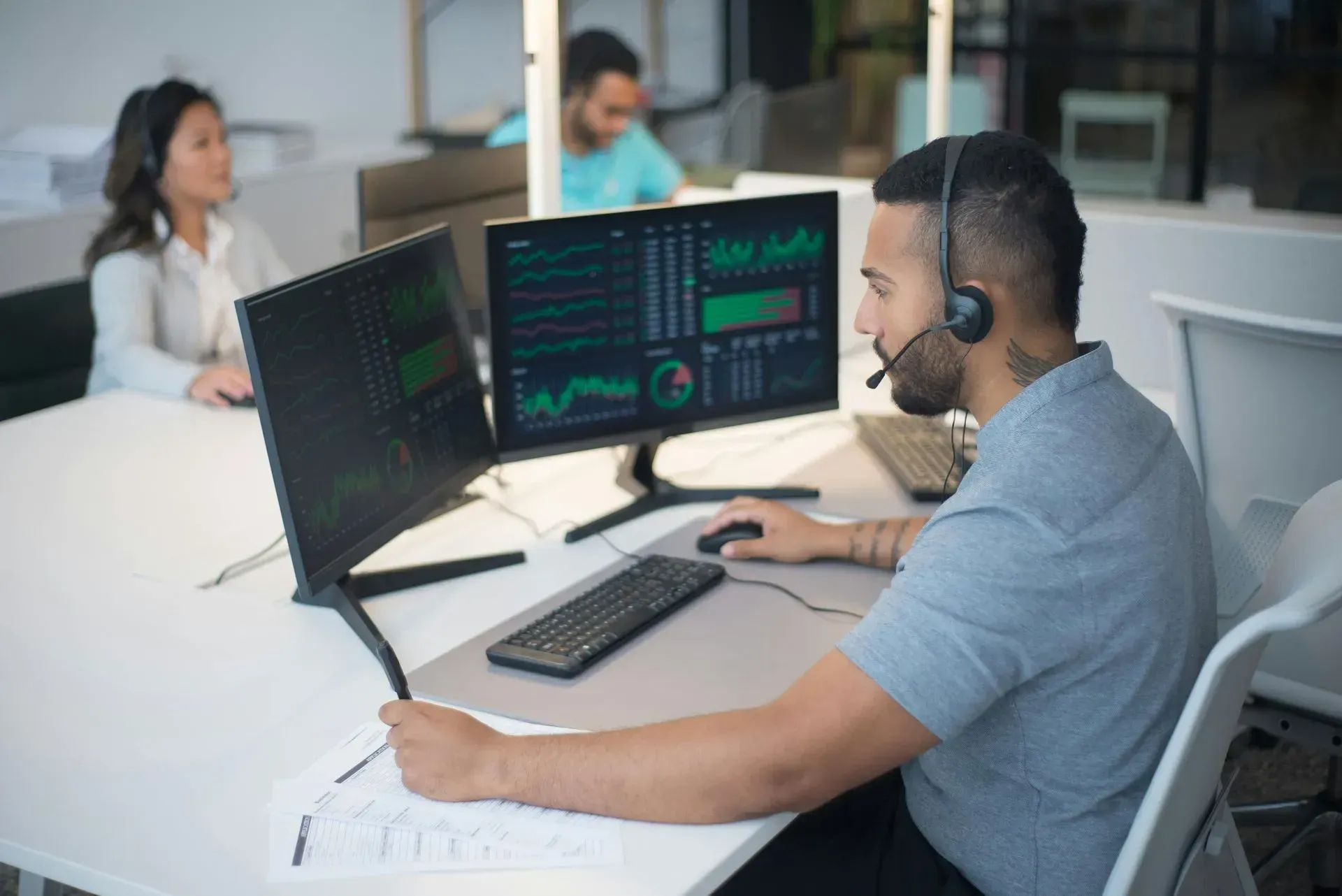 Office workers monitoring multiple computer screens in a modern workspace