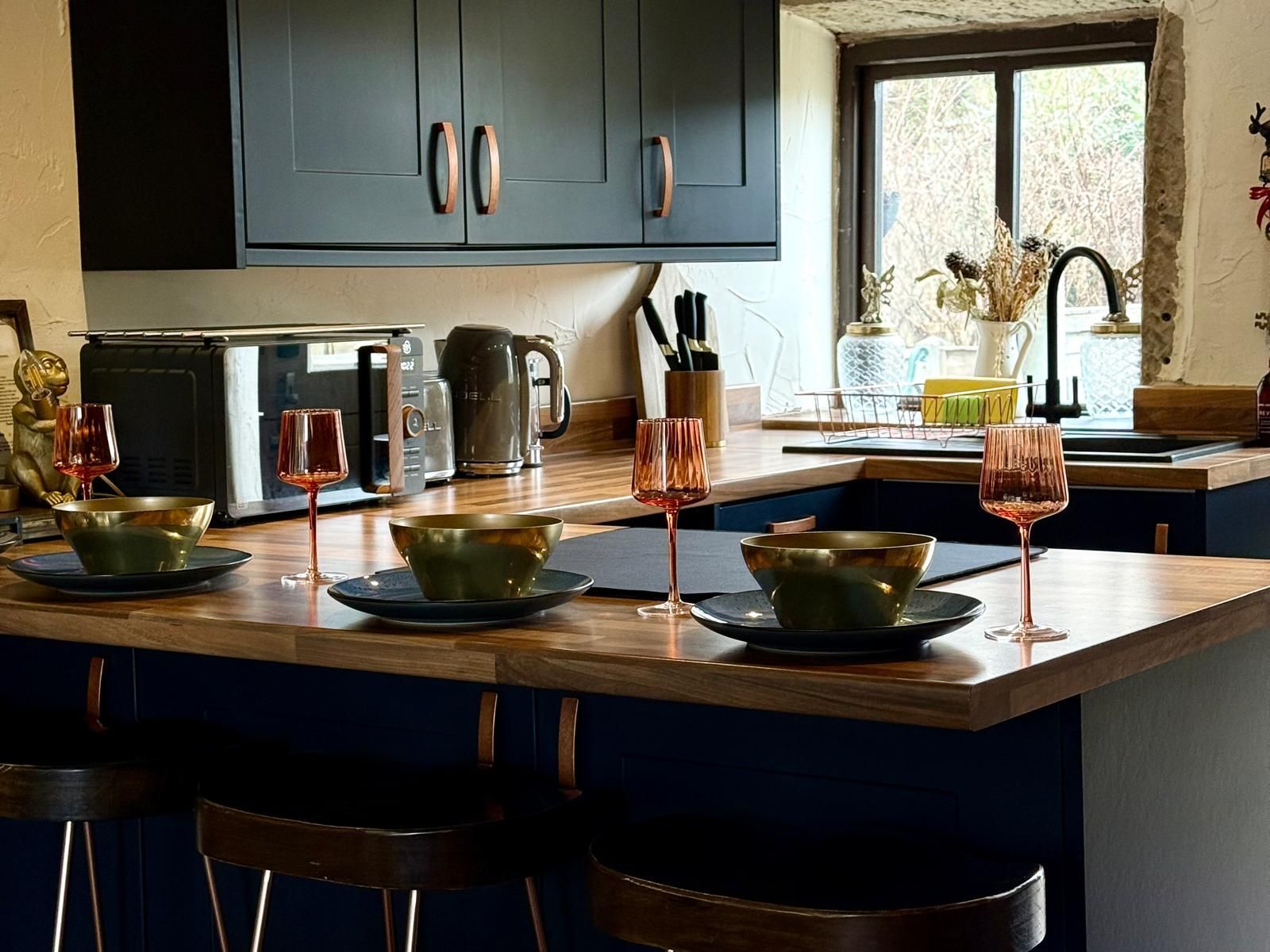 Modern kitchen with island, green bowls, dark cabinets, and sunlight by the sink